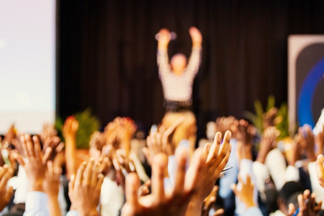 attendees with hands up at event