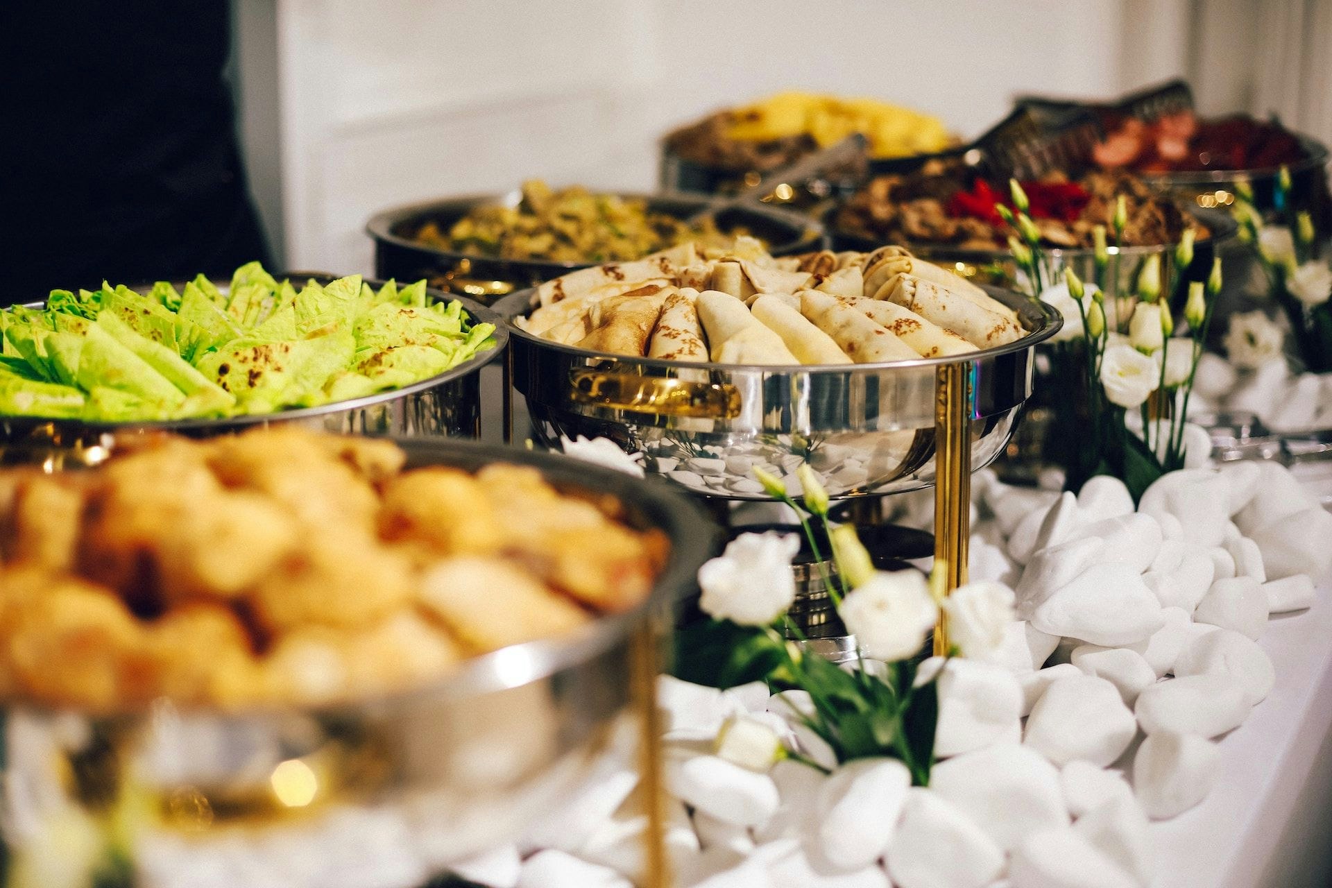 a table of different dishes in silver bowls at an event