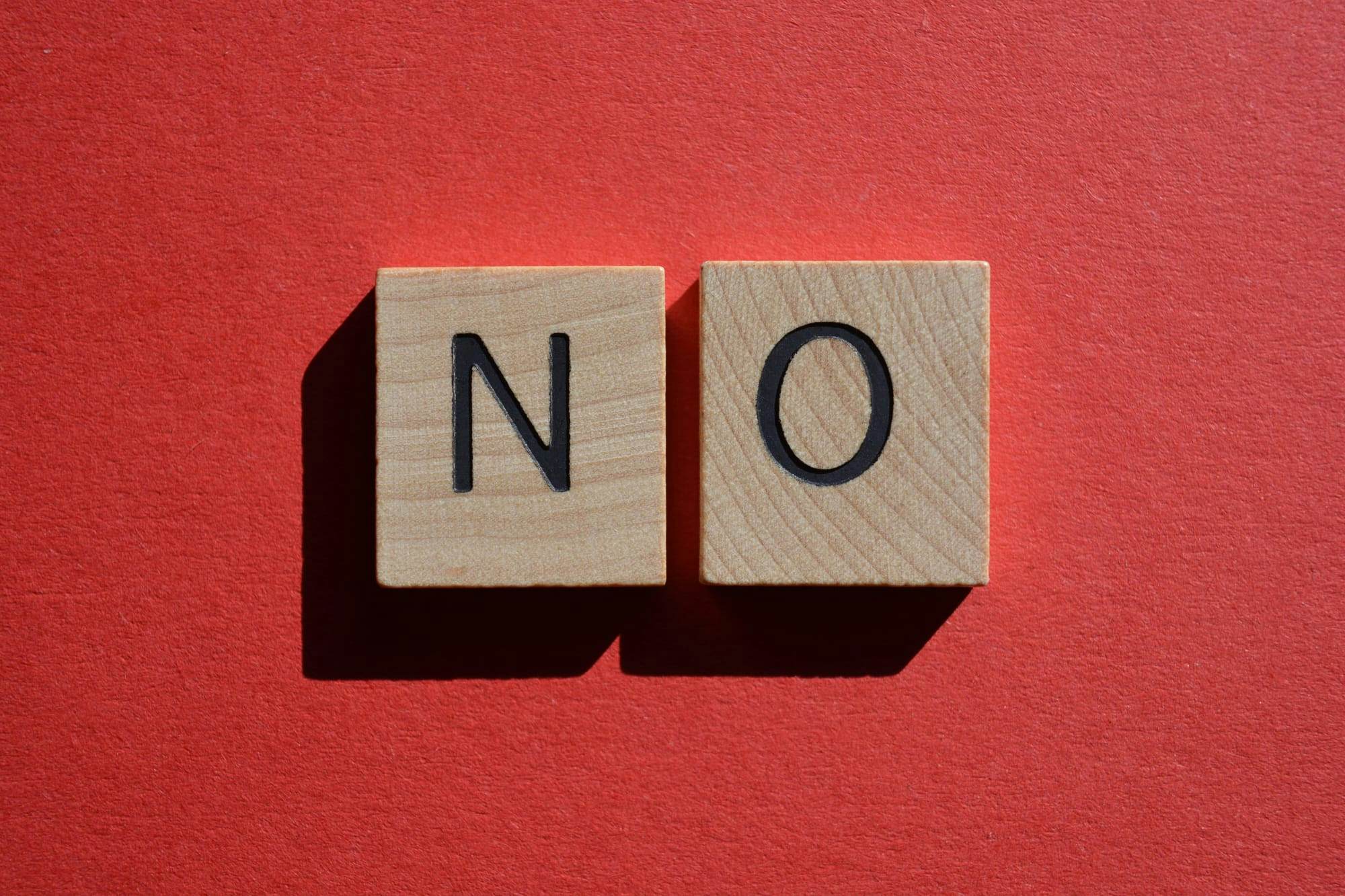 Two scrabble pieces spelling "No" on red background