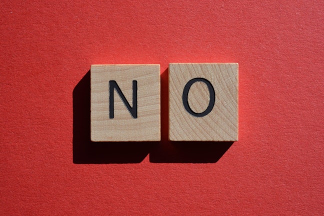Two scrabble pieces spelling "No" on red background