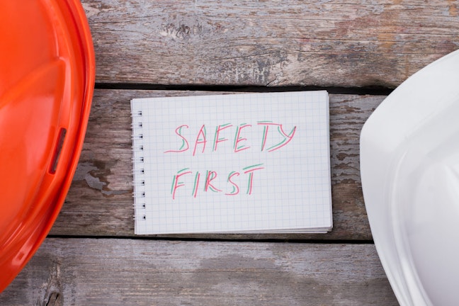 Words "Safety First" written on paper on a wooden background