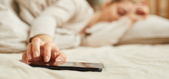 Woman reaching for phone in bed
