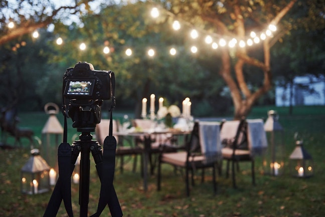 Evening set up for dinner in a garden for wedding with camera. 