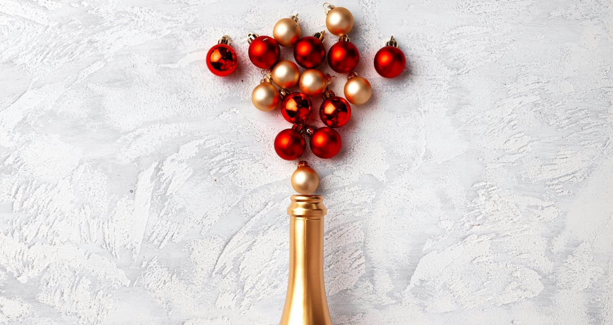 champagne bottle popping with red and gold baubles